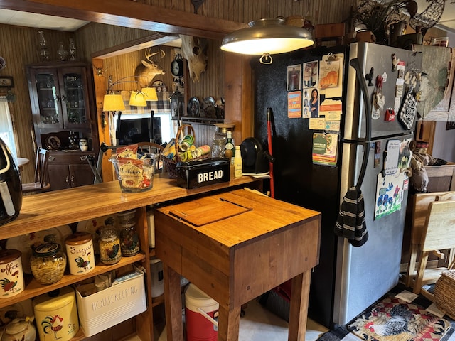 kitchen with freestanding refrigerator, wood walls, and butcher block counters