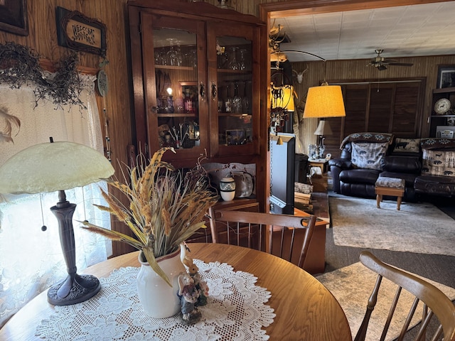 dining room with ceiling fan, carpet flooring, and wood walls
