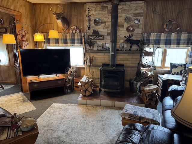 carpeted living room featuring wood walls and a wood stove