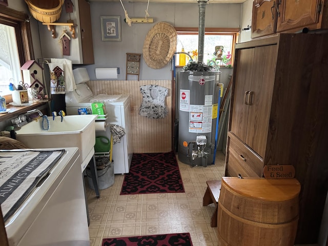 laundry room with washer and dryer, cabinet space, gas water heater, a wainscoted wall, and light floors