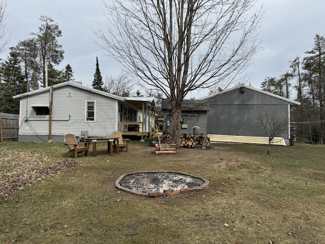 rear view of property with an outdoor fire pit and a yard