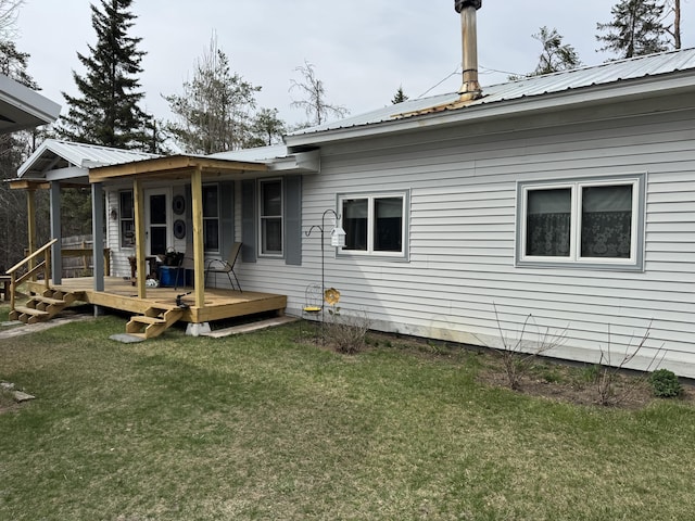 rear view of house featuring a wooden deck, a yard, and metal roof