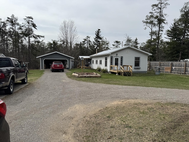 bungalow-style house featuring dirt driveway, an outbuilding, a carport, fence, and a front lawn