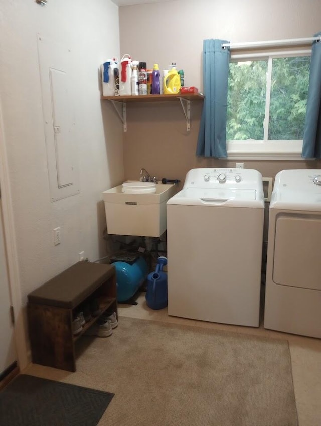 laundry area with laundry area, a sink, washing machine and dryer, and electric panel