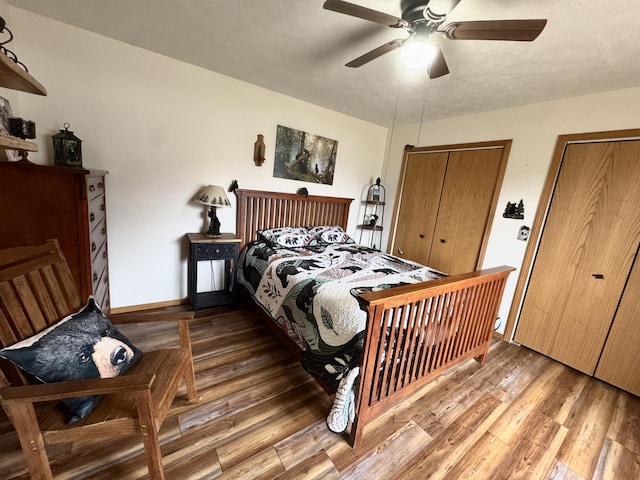 bedroom with light wood-style floors, baseboards, a ceiling fan, and multiple closets