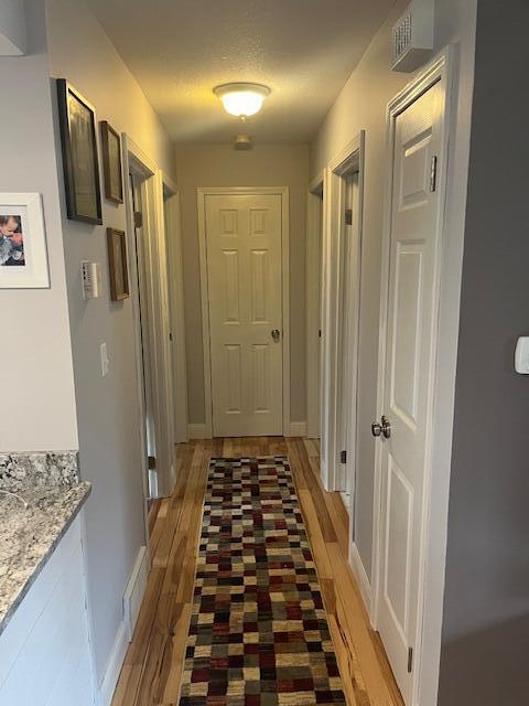 corridor featuring light wood-style flooring, baseboards, and visible vents
