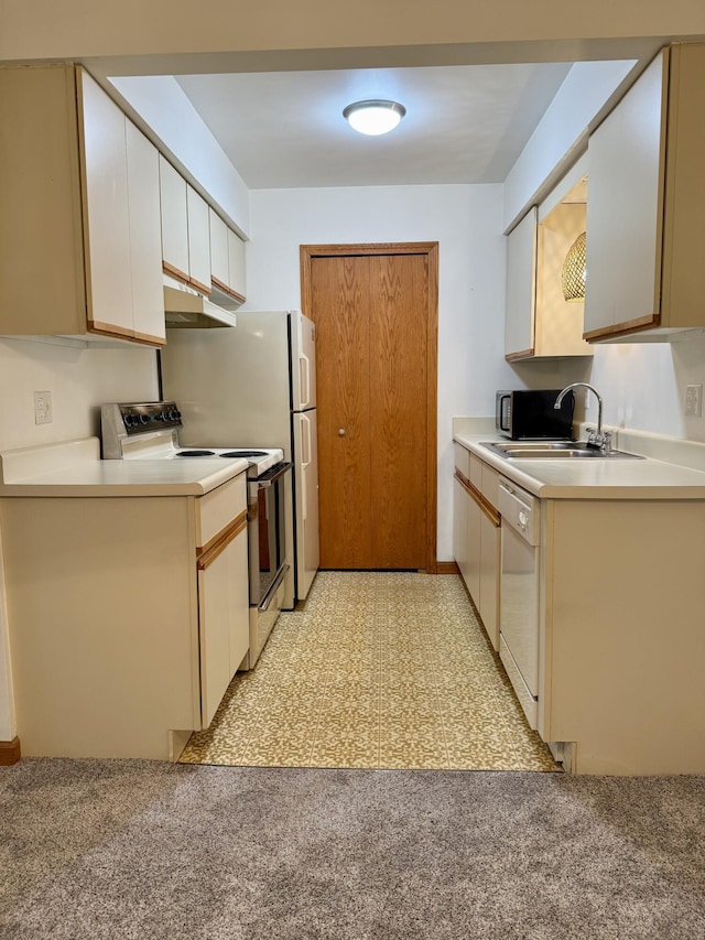 kitchen with a sink, white appliances, under cabinet range hood, light countertops, and white cabinets