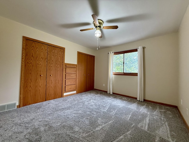 unfurnished bedroom with two closets, visible vents, ceiling fan, and carpet floors