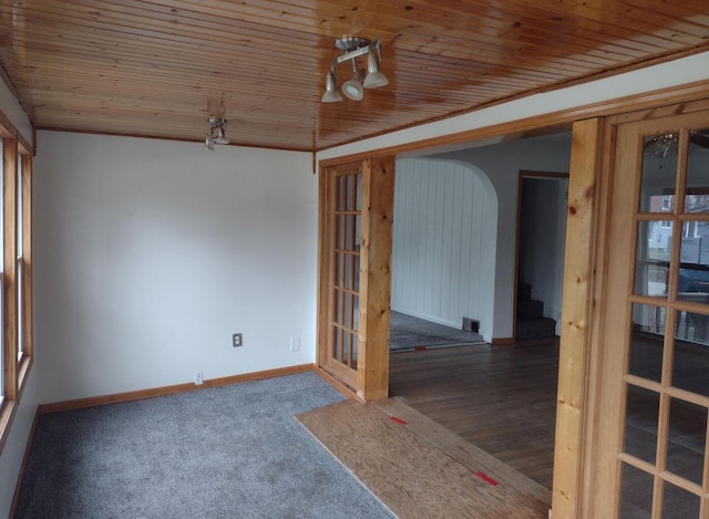 carpeted spare room featuring wooden ceiling, stairway, baseboards, and arched walkways