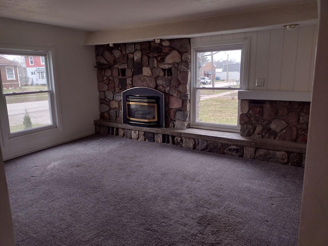 living area with a stone fireplace, heating unit, and carpet floors