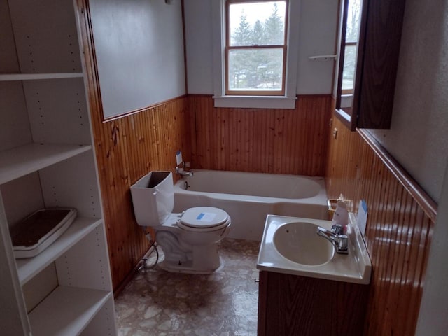 bathroom with toilet, wainscoting, a tub to relax in, a sink, and wooden walls
