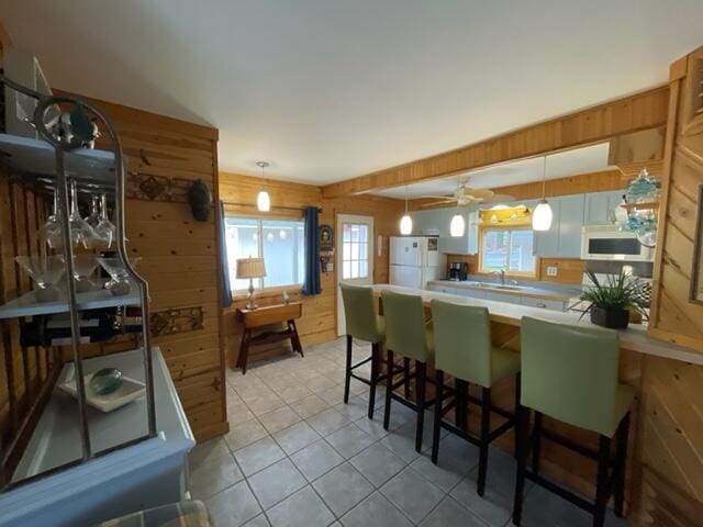 kitchen with a peninsula, white appliances, pendant lighting, ceiling fan, and light tile patterned floors