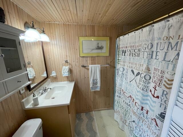 full bath with toilet, wooden walls, and wooden ceiling