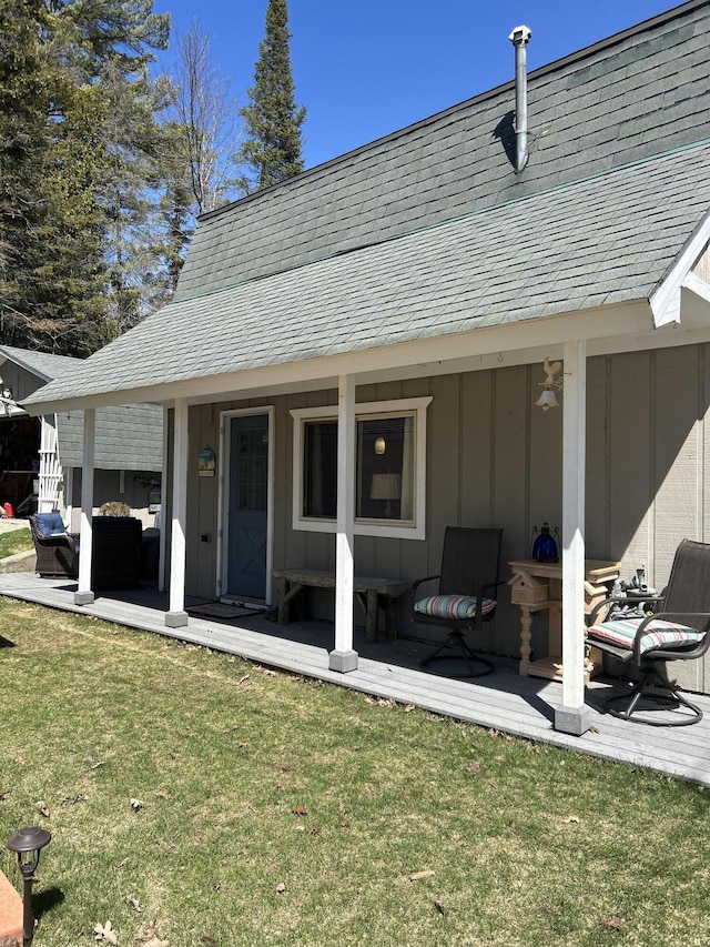 rear view of house with a lawn, board and batten siding, a shingled roof, and outdoor lounge area