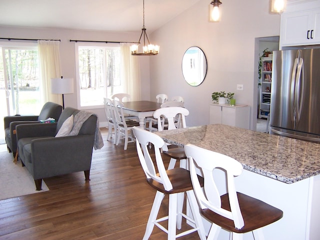 interior space with vaulted ceiling, dark wood-style flooring, a kitchen bar, and freestanding refrigerator