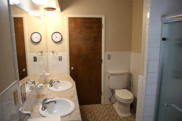 full bathroom featuring tile walls, toilet, a wainscoted wall, double vanity, and tile patterned flooring
