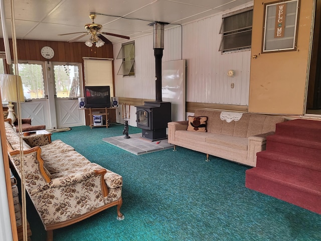 10675 N Shady Ln, Irons, MI 49644 - living area featuring ceiling fan, wooden walls, carpet, and a wood stove