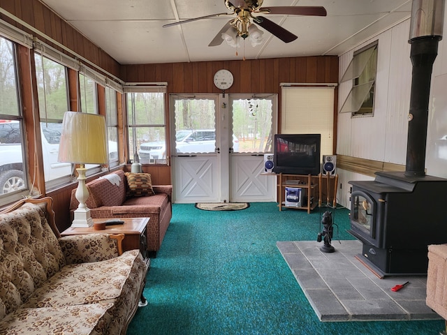 10675 N Shady Ln, Irons, MI 49644 - carpeted living room featuring a wood stove, wood walls, and a ceiling fan