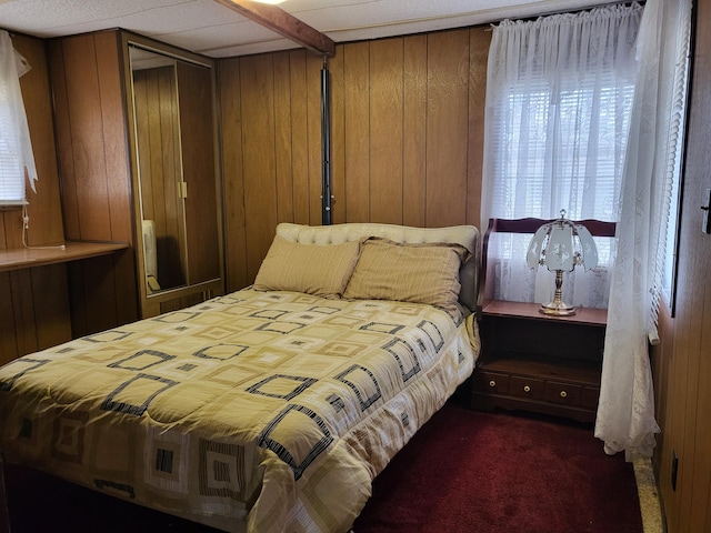 10675 N Shady Ln, Irons, MI 49644 - bedroom featuring wood walls, dark colored carpet, and a closet