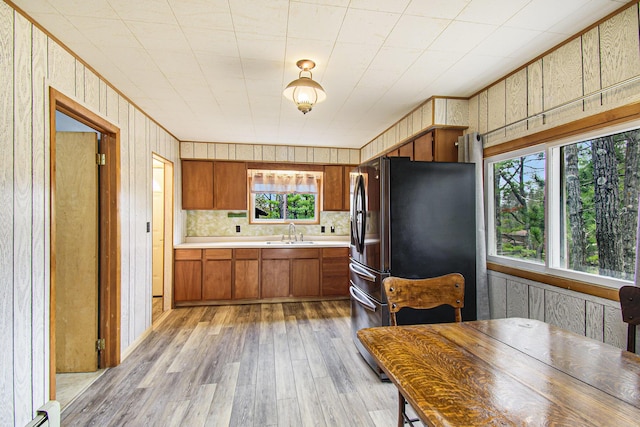 kitchen with a sink, brown cabinetry, freestanding refrigerator, light wood finished floors, and light countertops