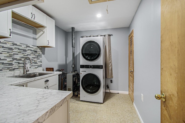 laundry room with light tile patterned floors, baseboards, a sink, laundry area, and stacked washer / drying machine