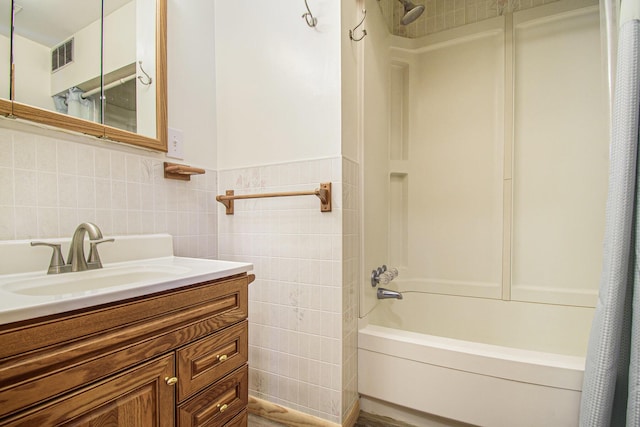full bath with tile walls, shower / tub combo with curtain, vanity, and visible vents