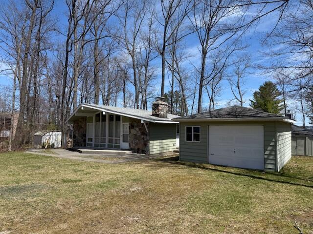 back of property with a sunroom, a chimney, and a lawn