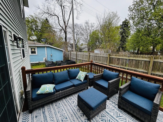 wooden deck with a fenced backyard, an outdoor hangout area, and an outbuilding