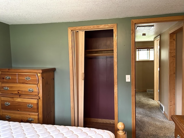 bedroom featuring carpet, a closet, a textured ceiling, visible vents, and baseboards
