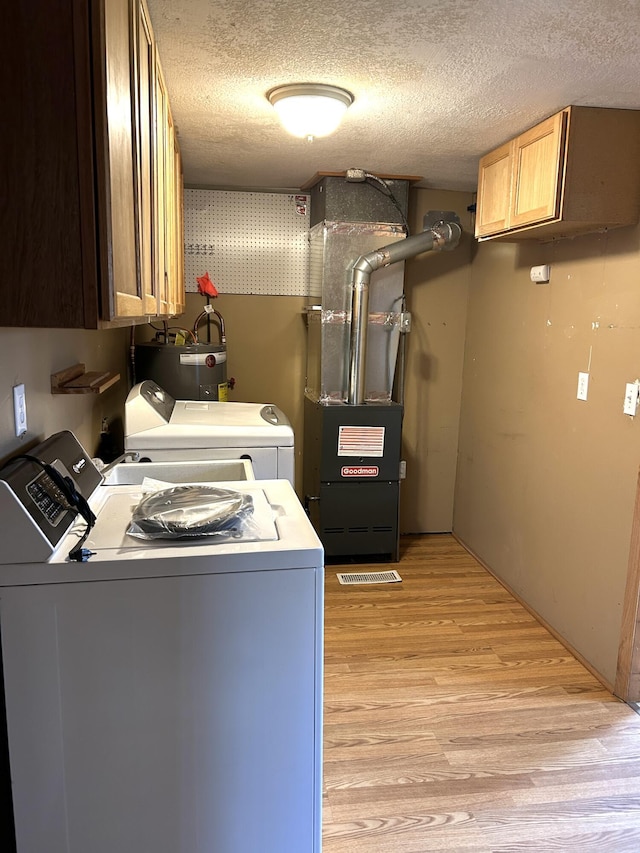 laundry area with cabinet space, independent washer and dryer, a textured ceiling, heating unit, and light wood-style flooring