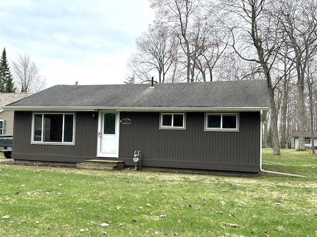 ranch-style home with a shingled roof and a front lawn