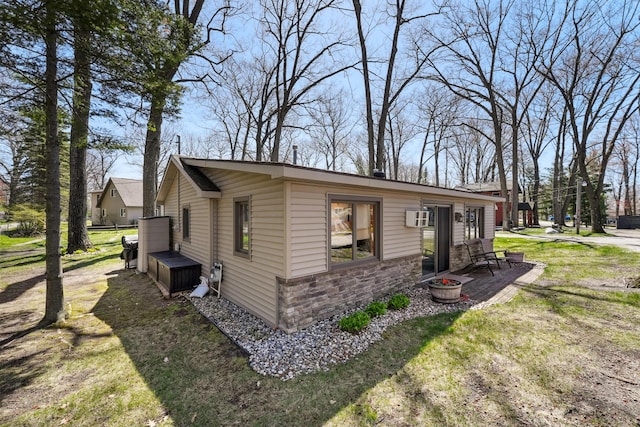 135 Alpena Trl, Houghton Lake, MI 48629 - view of side of property with stone siding and a wall mounted AC