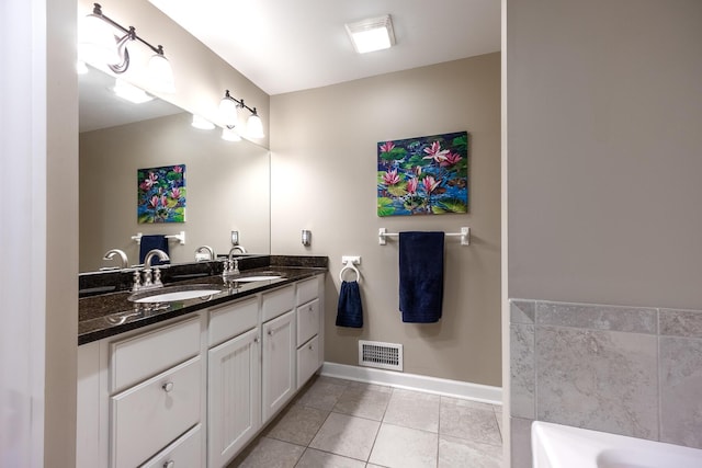bathroom with tile patterned floors, baseboards, double vanity, and a tub to relax in