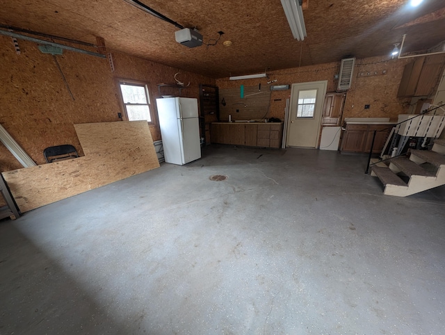 garage with freestanding refrigerator and a garage door opener