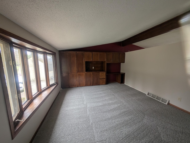 unfurnished living room featuring healthy amount of natural light, light carpet, a textured ceiling, and baseboards