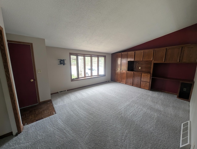 unfurnished living room featuring carpet, lofted ceiling, a textured ceiling, and baseboards