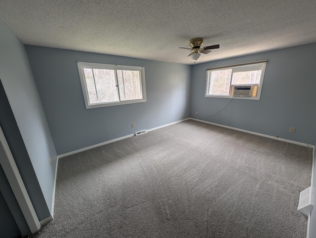 carpeted spare room with a textured ceiling, a ceiling fan, baseboards, and cooling unit