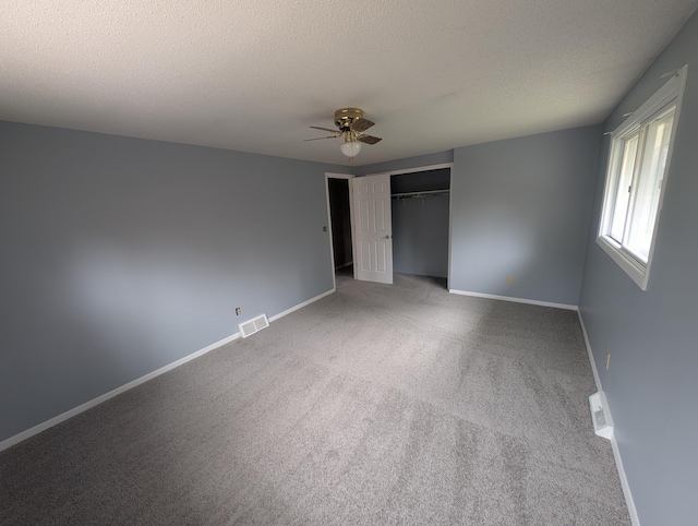 unfurnished bedroom featuring carpet flooring, baseboards, a closet, a textured ceiling, and ceiling fan