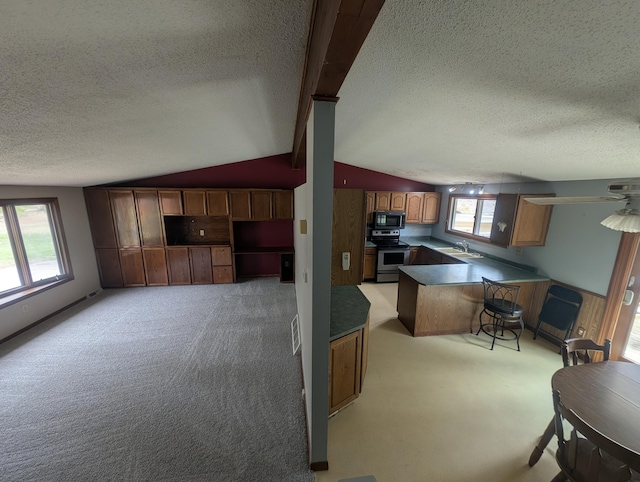 kitchen with stainless steel range with electric cooktop, black microwave, a textured ceiling, light colored carpet, and a sink