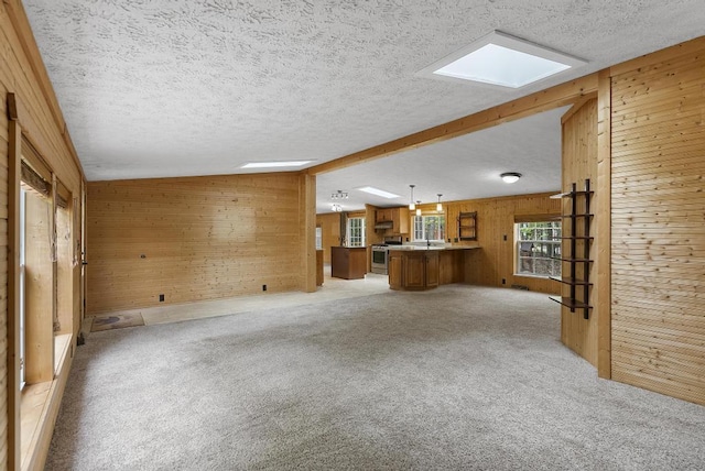 1505 Shawnee Dr, Indian River, MI 49749 - unfurnished living room with wooden walls, light colored carpet, a textured ceiling, and a skylight