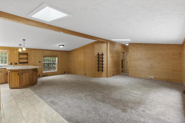 1505 Shawnee Dr, Indian River, MI 49749 - unfurnished living room featuring wood walls, plenty of natural light, a skylight, beamed ceiling, and a textured ceiling