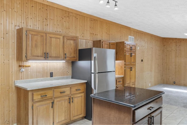 1505 Shawnee Dr, Indian River, MI 49749 - kitchen featuring wooden walls, freestanding refrigerator, a textured ceiling, a kitchen island, and dark stone countertops