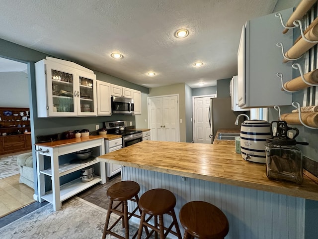 1243 Euclid Ave, Grayling, MI 49738 - kitchen featuring appliances with stainless steel finishes, wood counters, a breakfast bar area, a peninsula, and a textured ceiling