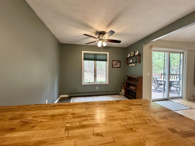 1243 Euclid Ave, Grayling, MI 49738 - unfurnished room with a baseboard heating unit, a ceiling fan, healthy amount of natural light, a textured ceiling, and baseboards
