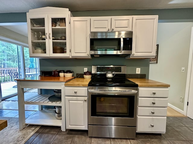 1243 Euclid Ave, Grayling, MI 49738 - kitchen with stainless steel appliances, wooden counters, white cabinetry, glass insert cabinets, and dark tile patterned flooring