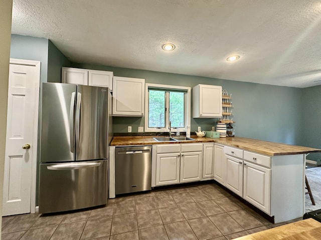 1243 Euclid Ave, Grayling, MI 49738 - kitchen with stainless steel appliances, a sink, a textured ceiling, a peninsula, and white cabinetry