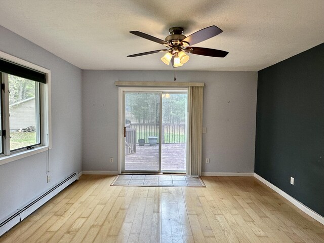 1243 Euclid Ave, Grayling, MI 49738 - doorway to outside featuring a baseboard radiator, wood finished floors, a ceiling fan, baseboards, and a textured ceiling