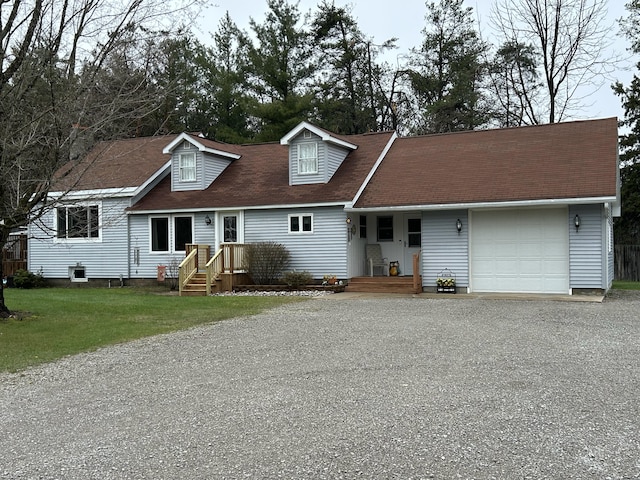 cape cod-style house featuring a garage, gravel driveway, and a front yard