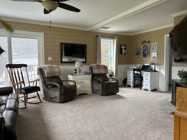 carpeted living room with wallpapered walls, ceiling fan, and crown molding