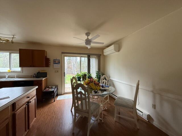 206 Great Oak Dr, Roscommon, MI 48653 - dining area featuring a wall mounted air conditioner, ceiling fan, light wood-type flooring, and a baseboard heating unit